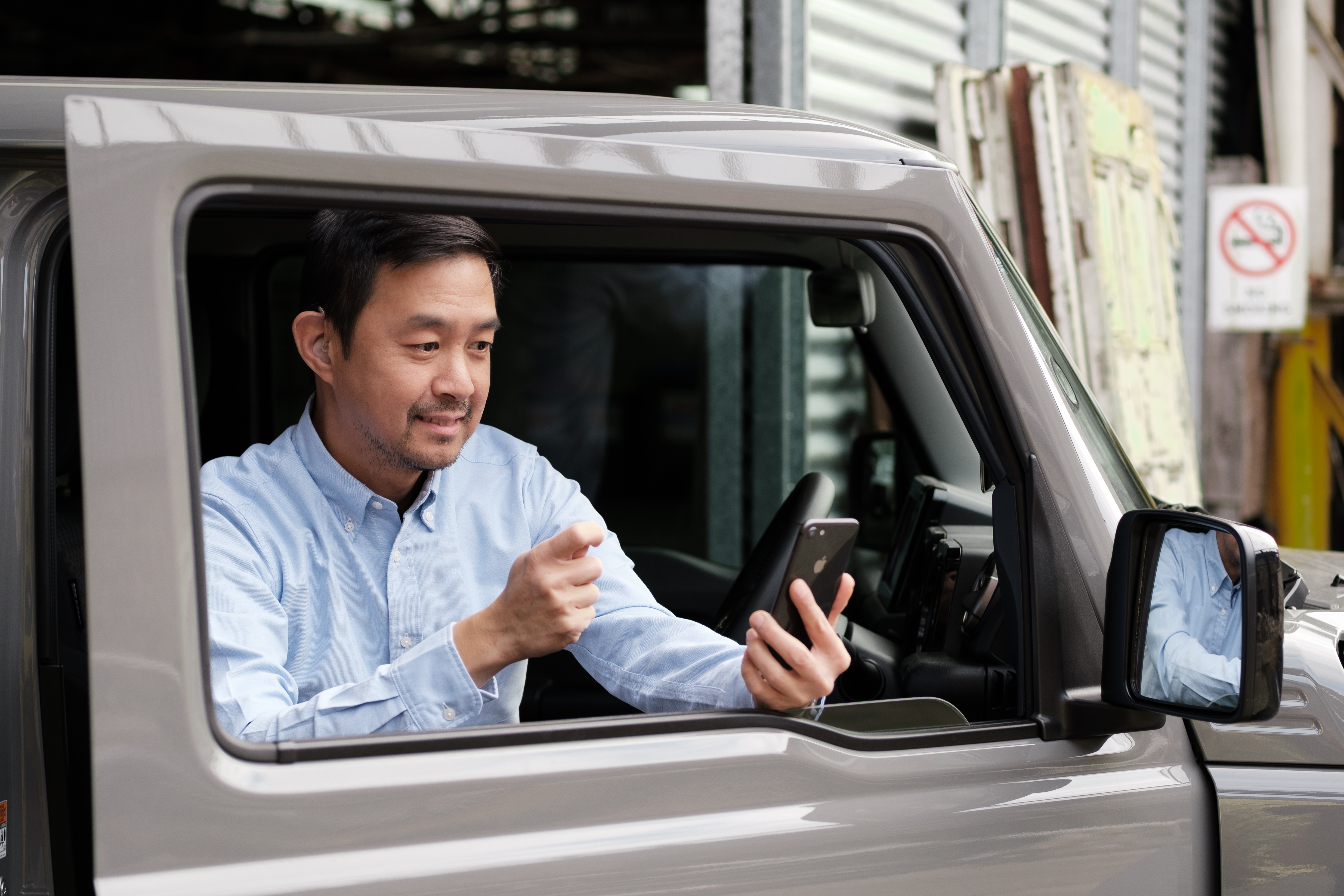 Asian man video call through Convo AU app in his grey Jeep.